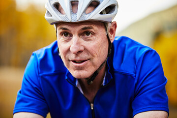 Close-up of senior man wearing bicycle helmet cycling in forest
