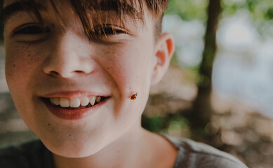 Close-up portrait of happy boy with insect on face