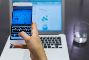 Cropped hand of businesswoman analyzing data over mobile phone in creative office