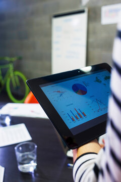 Cropped image of businesswoman analyzing data over tablet computer in creative office