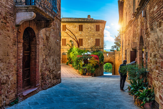Fototapeta Cozy street decorated with colorful flowers, Pienza, Tuscany, Italy, Europe. Narrow street in the charming town of Pienza in Tuscany. Beautiful streets of the small and historic village Pienza, Italy