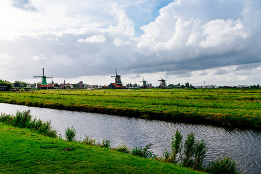 Scenic view of canal amidst green landscape against cloudy sky