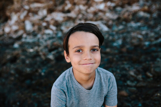 High angle portrait of boy sitting on rocks at beach