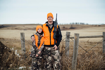 Portrait of smiling father and daughter wearing camouflage clothing standing on field