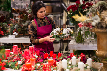 Store employee makes a Christmas composition with candles