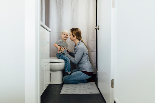 Side view of mother and son in bathroom seen through doorway at home
