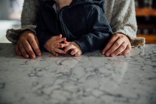 Midsection of mother and son by marble table at home