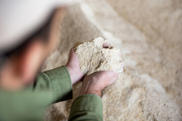 Farmer checks the quality of cornmeal in an animal feed warehouse