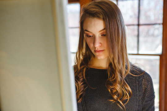 Close-up of woman painting on easel while standing in bedroom at home