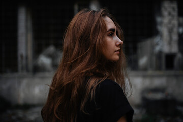 Side view of thoughtful woman looking away while standing against abandoned building