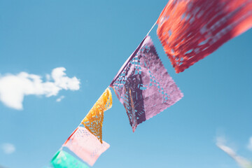 Low angle view of colorful flags hanging against blue sky during sunny day