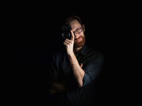 Man photographing with camera while standing against black background