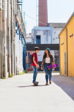 Woman talking with friend skateboarding on road amidst buildings in city