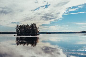 Scenic view of silhouette trees in calm lake against cloudy sky during sunny day