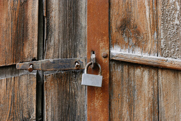 Old padlock on gates. A rusty lock hangs on the wooden door