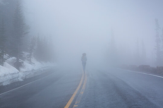 Rear view of woman walking on road in Yellowstone National park during foggy weather - Powered by Adobe