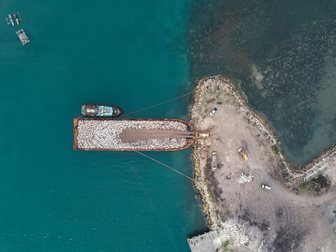 Aerial view of large barge with stones near Sumbawa island coastline