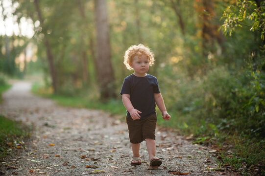 Toddler boy walk down a gravel trail in the middle of the woods