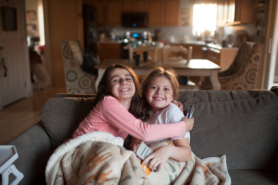 Friends sitting on couch hugging with happy expressions