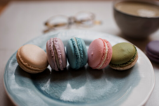 colourful macarons on plate with a drink