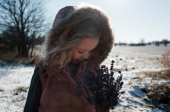 young girl outside holding lavender flowers looking down