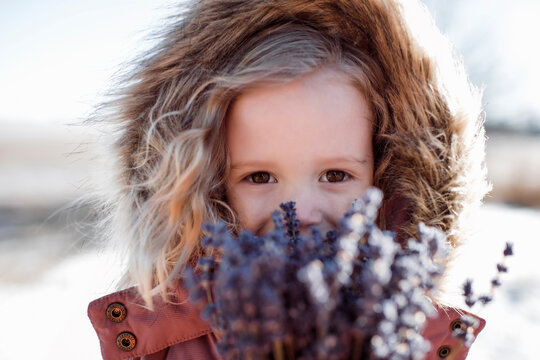 young girl outdoors holding a bunch of lavender flowers in winter