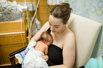 New mother holds child while sitting in neonatal intensive care unit
