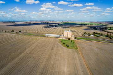 Looking down at the silos and country side in the Mallee on a cloudy day with shadows covering the land.