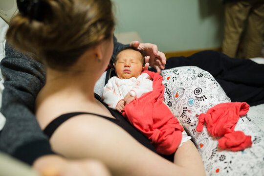 New parents cuddle with newborn baby girl in hospital room - Powered by Adobe