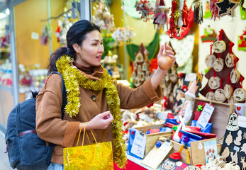 Portrait of smiling asian female choosing decorations at Christmas fair