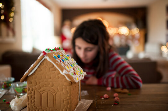 Gingerbread house being decorated by little girl during the holidays