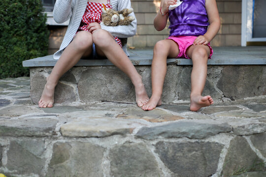 Two Girls Legs And Toes Sitting On Porch Steps In Shorts