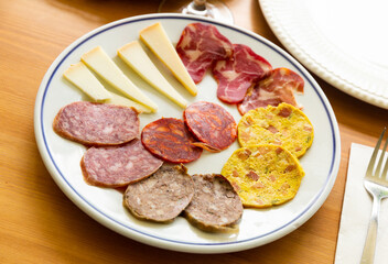 Obraz premium Traditional spanish snack tapas on a plate, selection of ham, salami and cheese