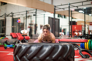 Young attractive woman lifting up a tractor tire