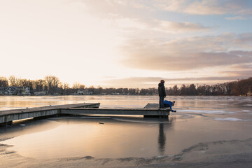 two boys at sunset on dock by frozen water