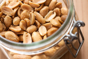 Open canning jar with fried salty peanuts. Selective focus. High angle