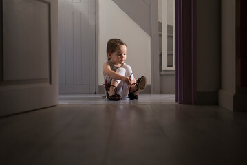 Young child tries on mother's shoes which are too big for her