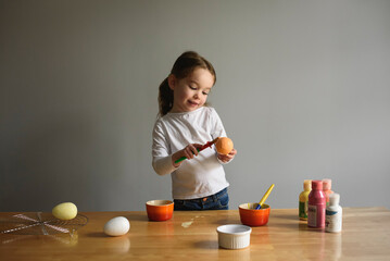 Child paints Easter Eggs at kitchen table craft