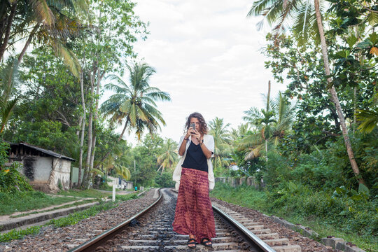 Caucasian girl taking picture with smartphone on train tracks Sri Lank