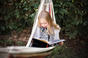 Young female relaxing in hammock reading a book