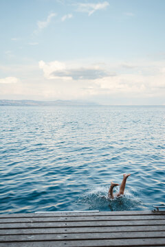a person's feet sticking out of the water as they dive in off a dock