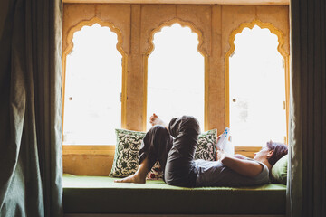 30 years old woman reading a book on couch in Indian hotel in Jodhpur
