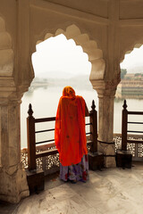 Indian woman with orange Sarees below a stone arch, Jaipur