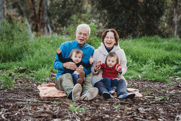 Portrait of senior active couple holding twin granddaughters outside