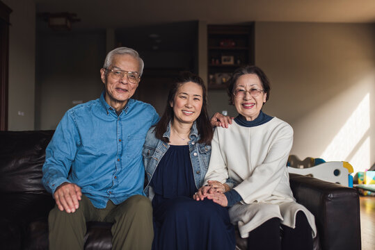 Portrait of adult daughter and her senior parents in living room