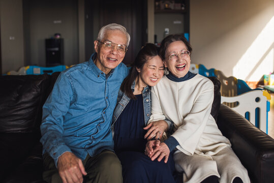 Portrait of adult daughter and her senior parents laughing