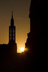 Silhouette of the church tower with the setting sun in the background.