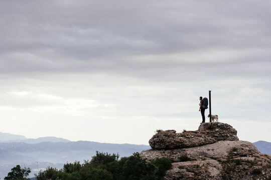 Young man and his dog contemplating landscape in Montserrat mountain