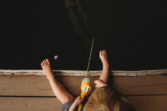 Overhead shot of young boy fishing off dock of lake