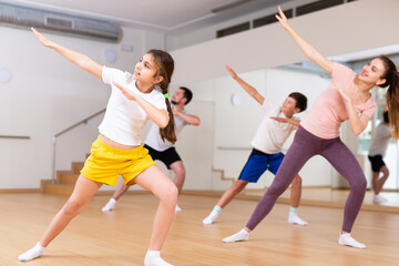 Naklejka na ściany i meble Portrait of tween girl doing exercises during family class in dance center
